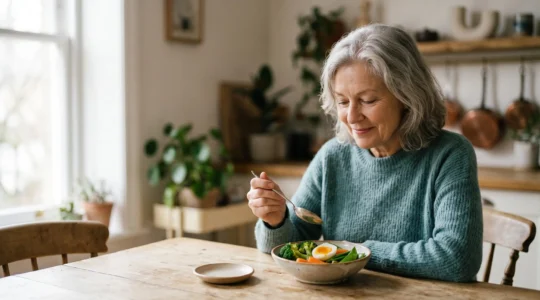 Personne senior savourant un repas léger et coloré à table dans une lumière douce, illustrant une alimentation adaptée aux troubles digestifs après 65 ans